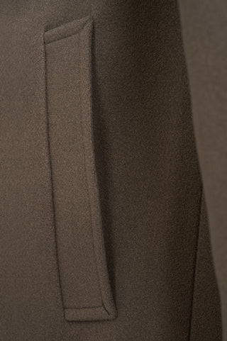 Close-up of a brown coat with a pocket detail on a matching background