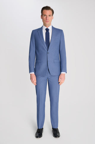 Man wearing a blue suit with a white shirt and black shoes on a light gray background